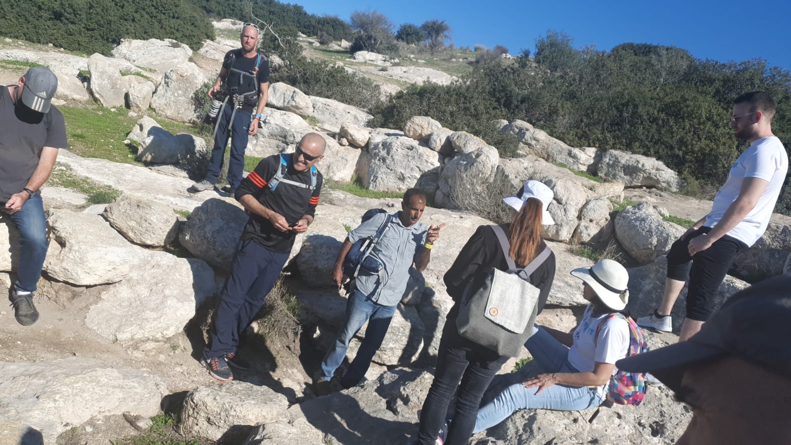 קבוצת אנשים יושבת על צלע גבעה סלעית.