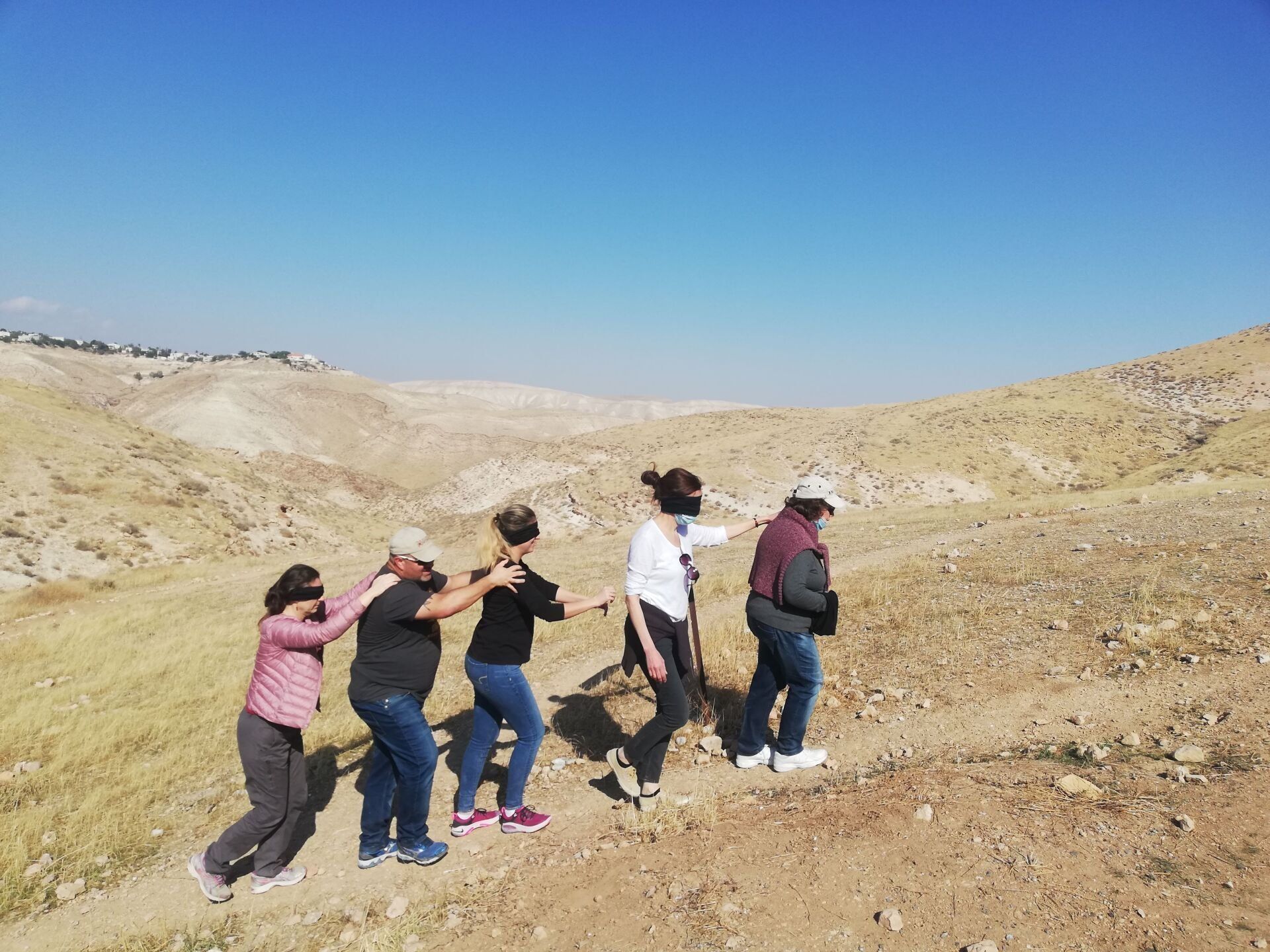 קבוצת אנשים צועדת בשביל עפר במדבר.