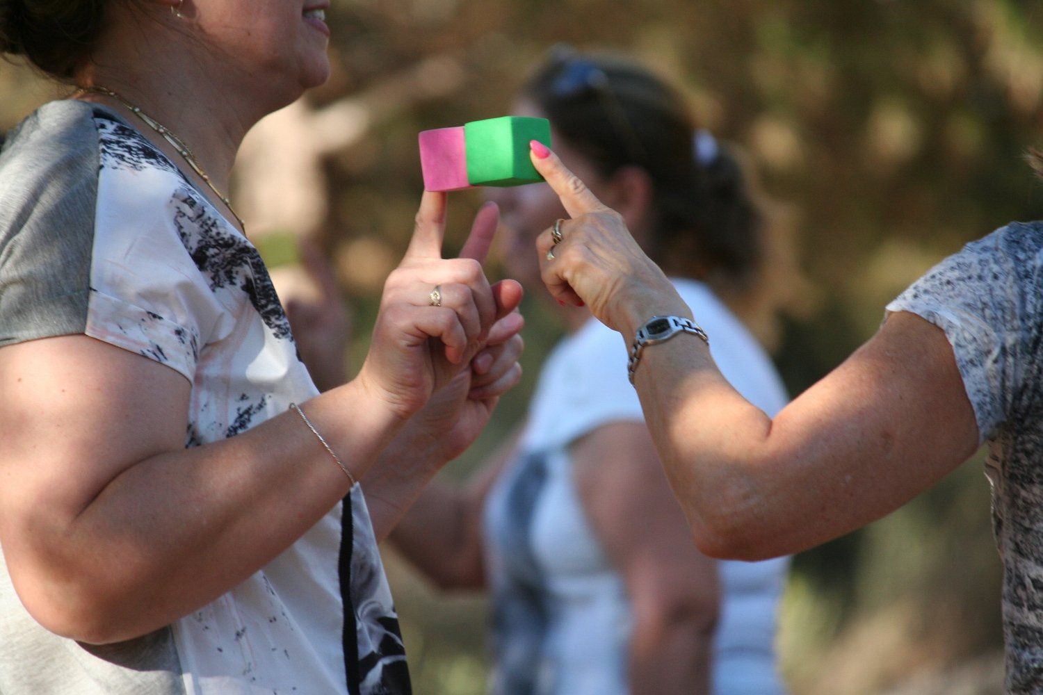אישה מחזיקה בידה קובייה ורודה וירוקה.