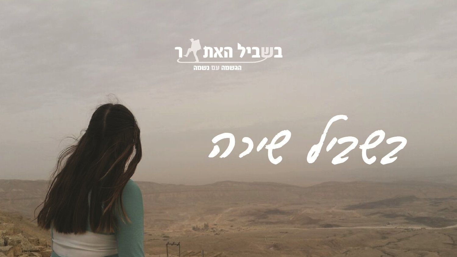 אישה יושבת על ראש גבעה ומסתכלת על הנוף.