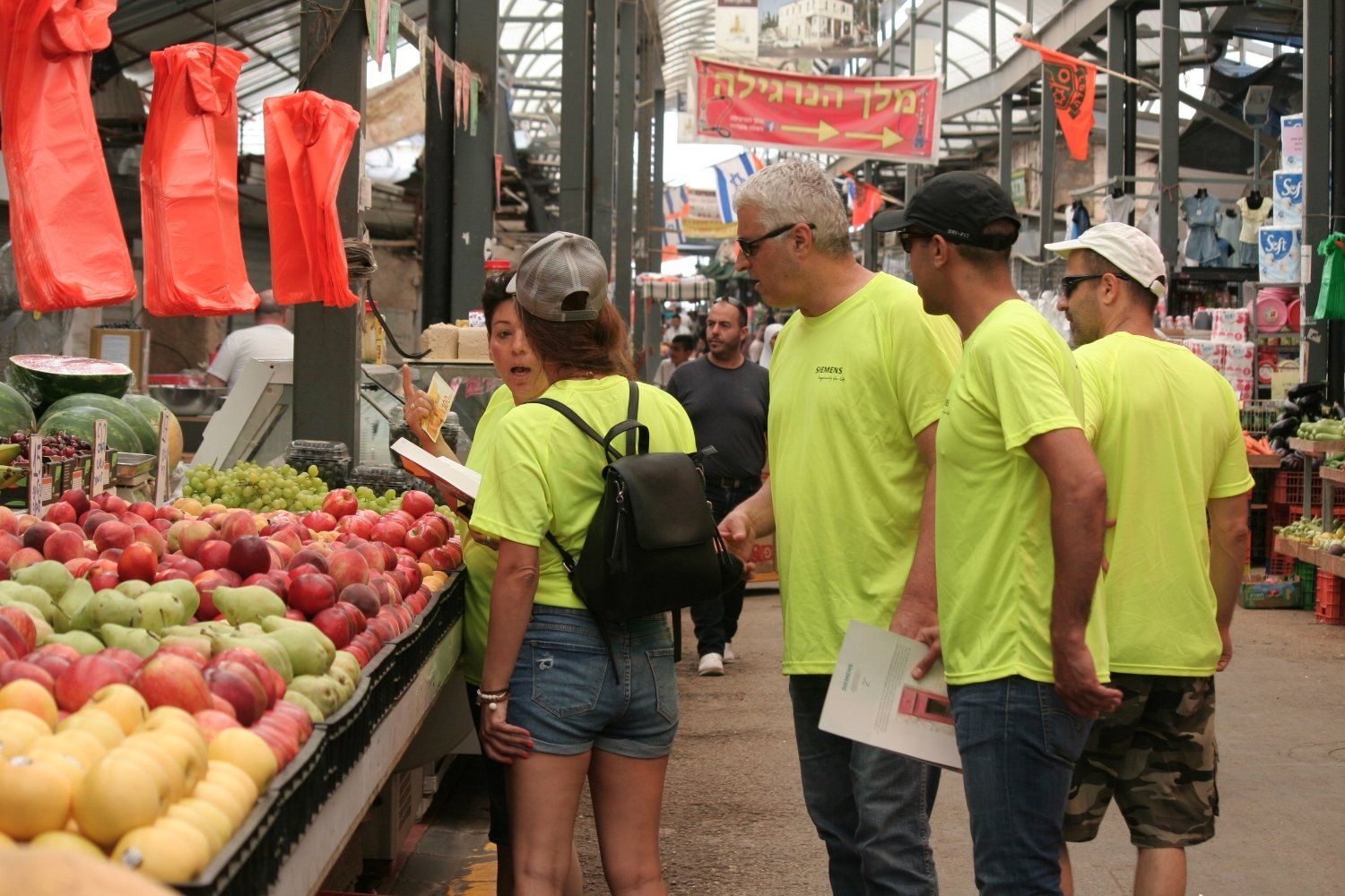 קבוצת אנשים עומדת מול דוכן פירות.