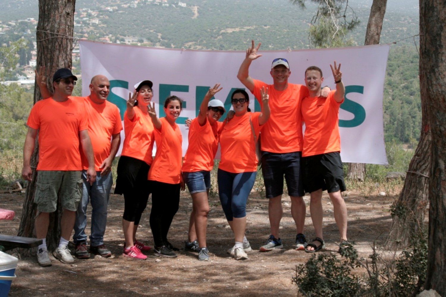 קבוצה של אנשים שלובשים חולצות כתומות מצטלמות