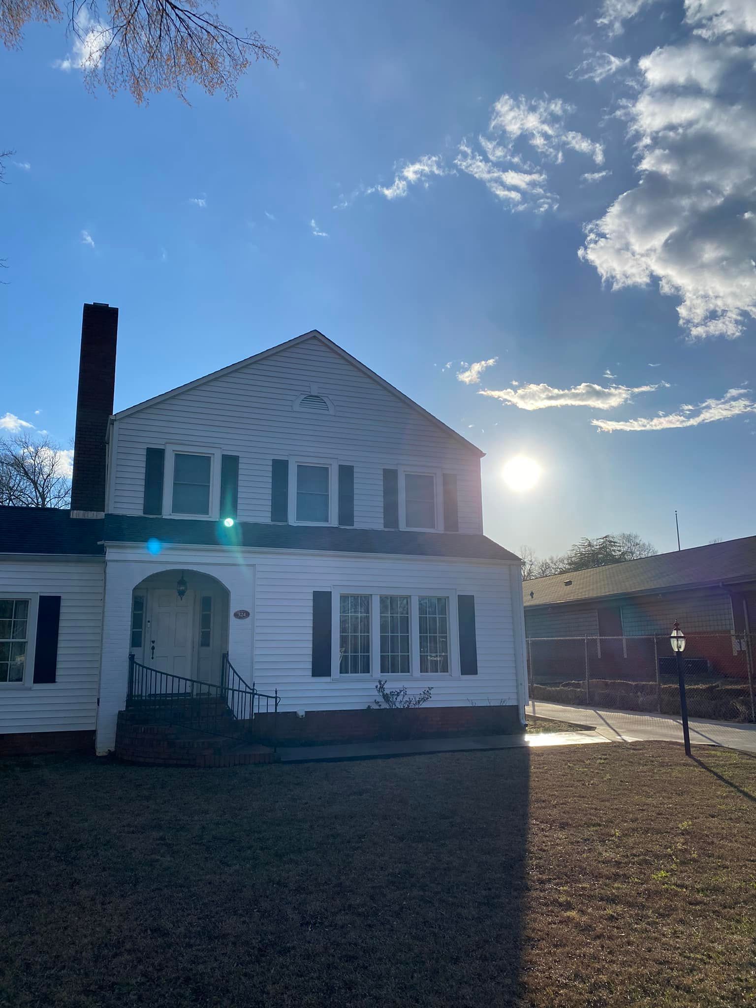 A white house with a blue sky and clouds in the background