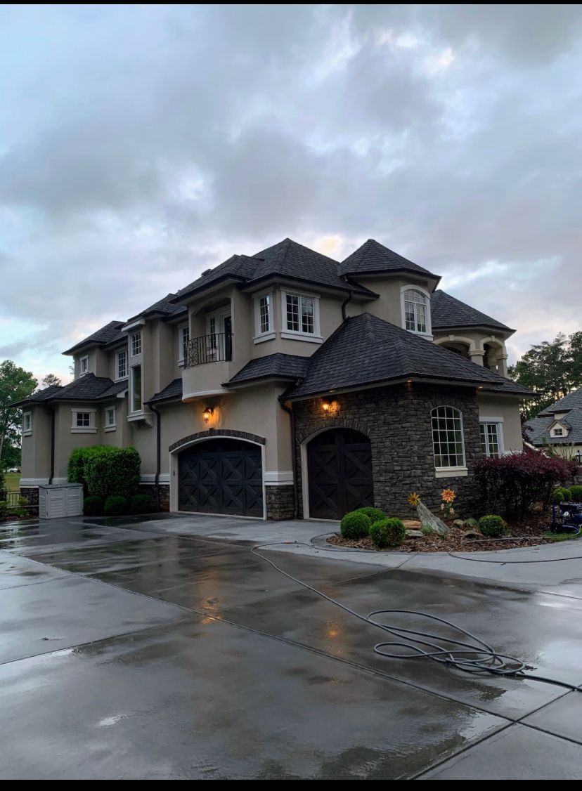 A large house with a gray roof is sitting on a rainy day.