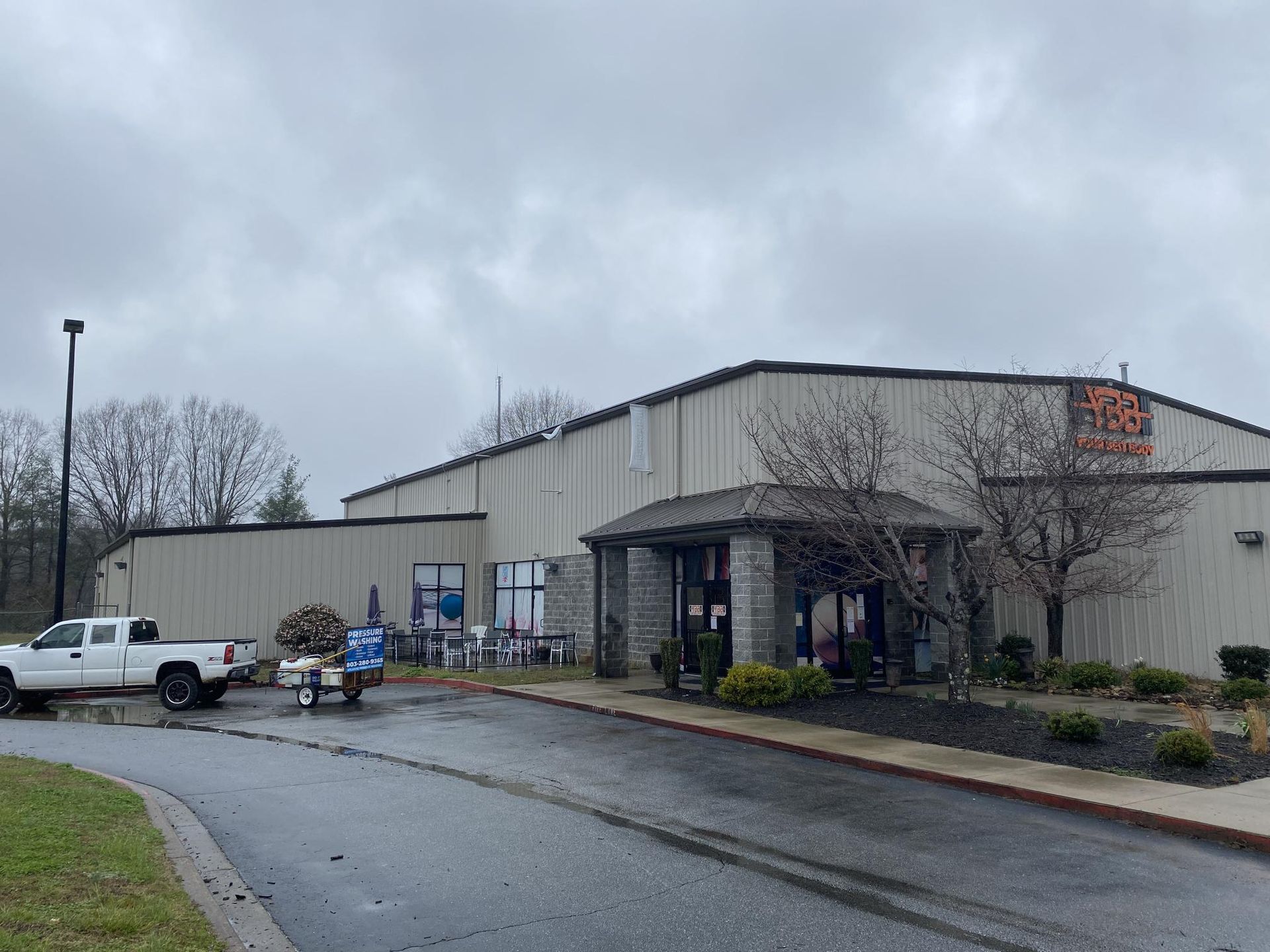 A white truck is parked in front of a large building on a cloudy day.