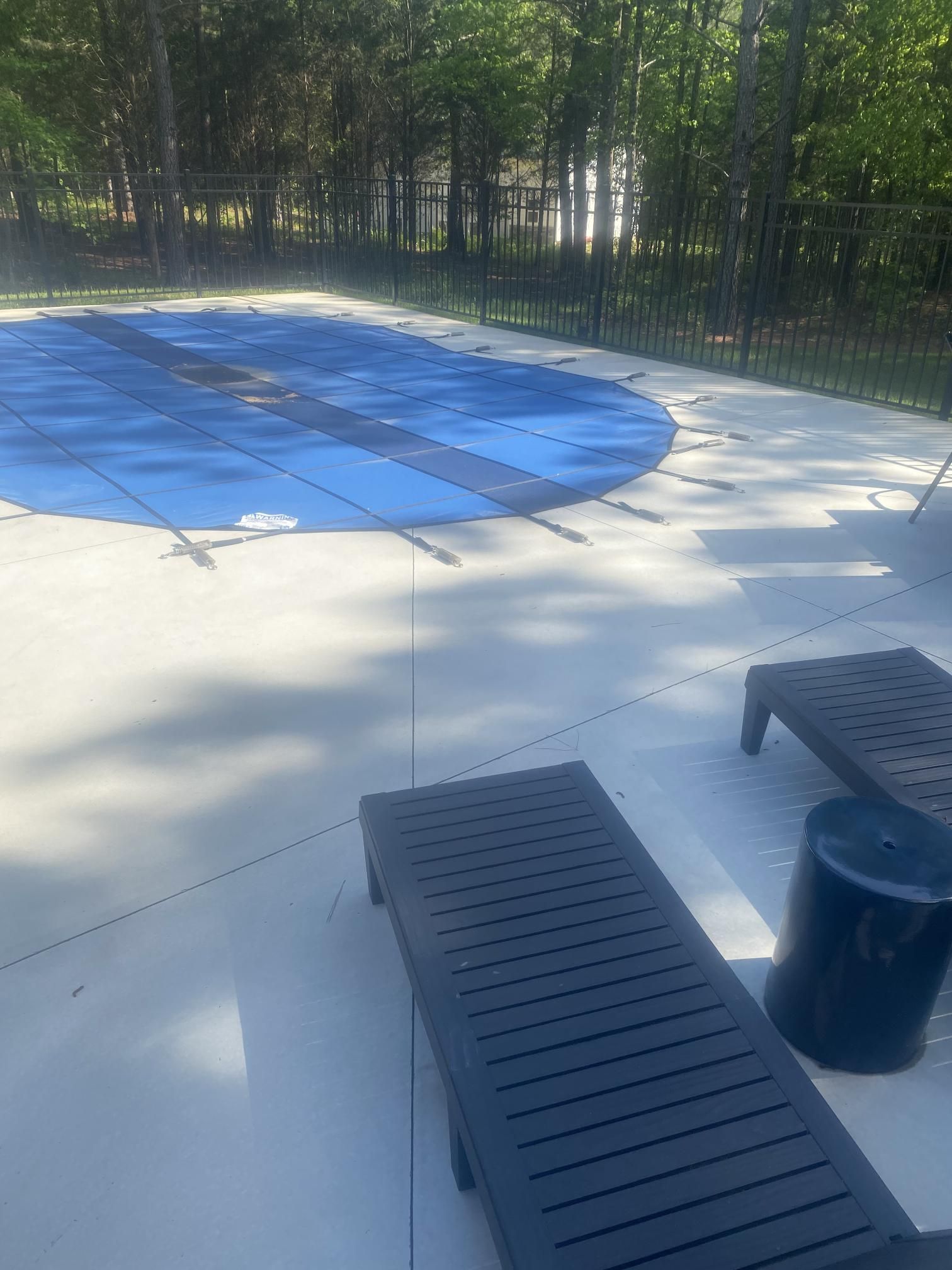 A swimming pool with a blue cover and two lounge chairs