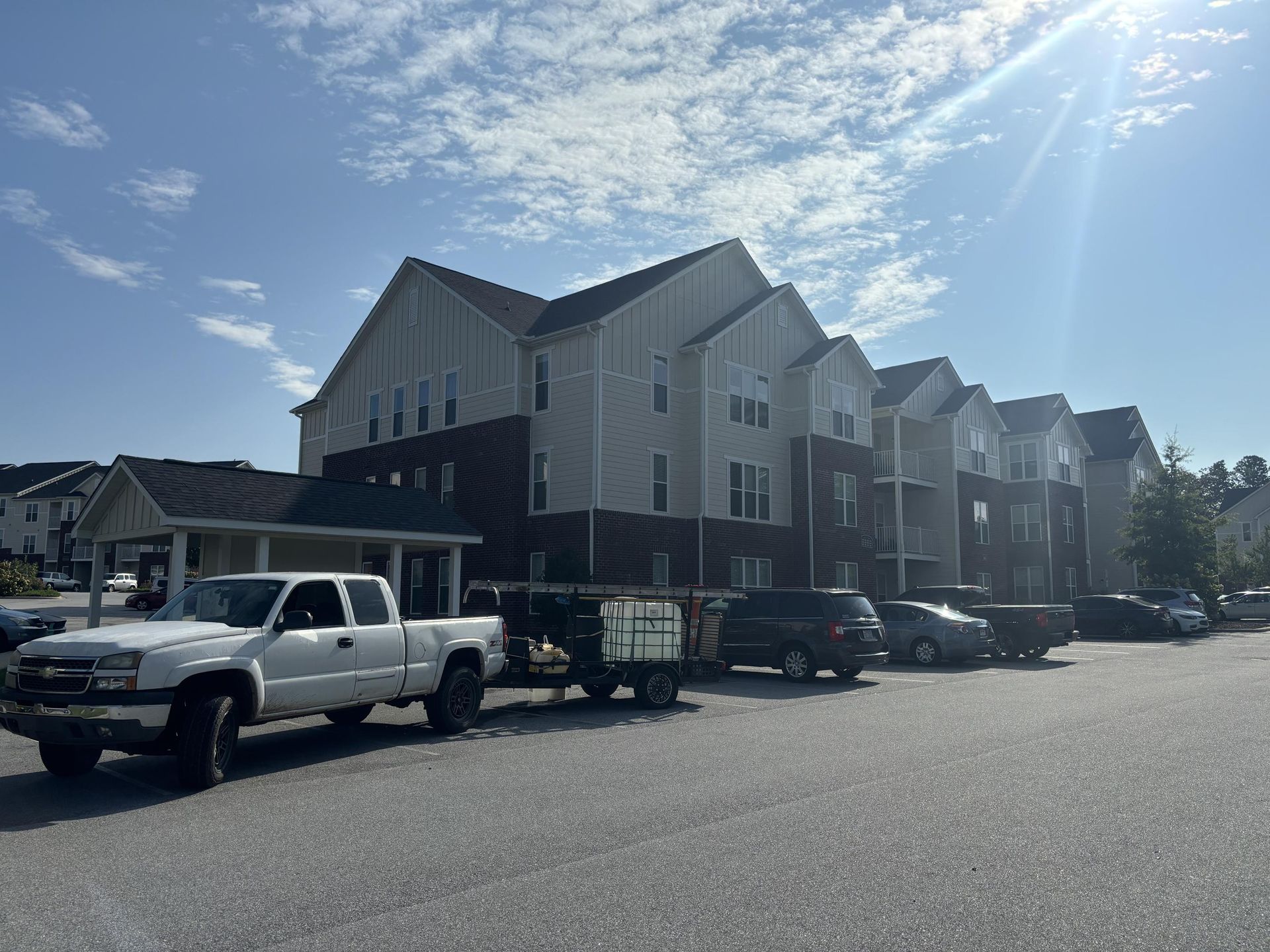 A white truck is parked in front of a large apartment building.