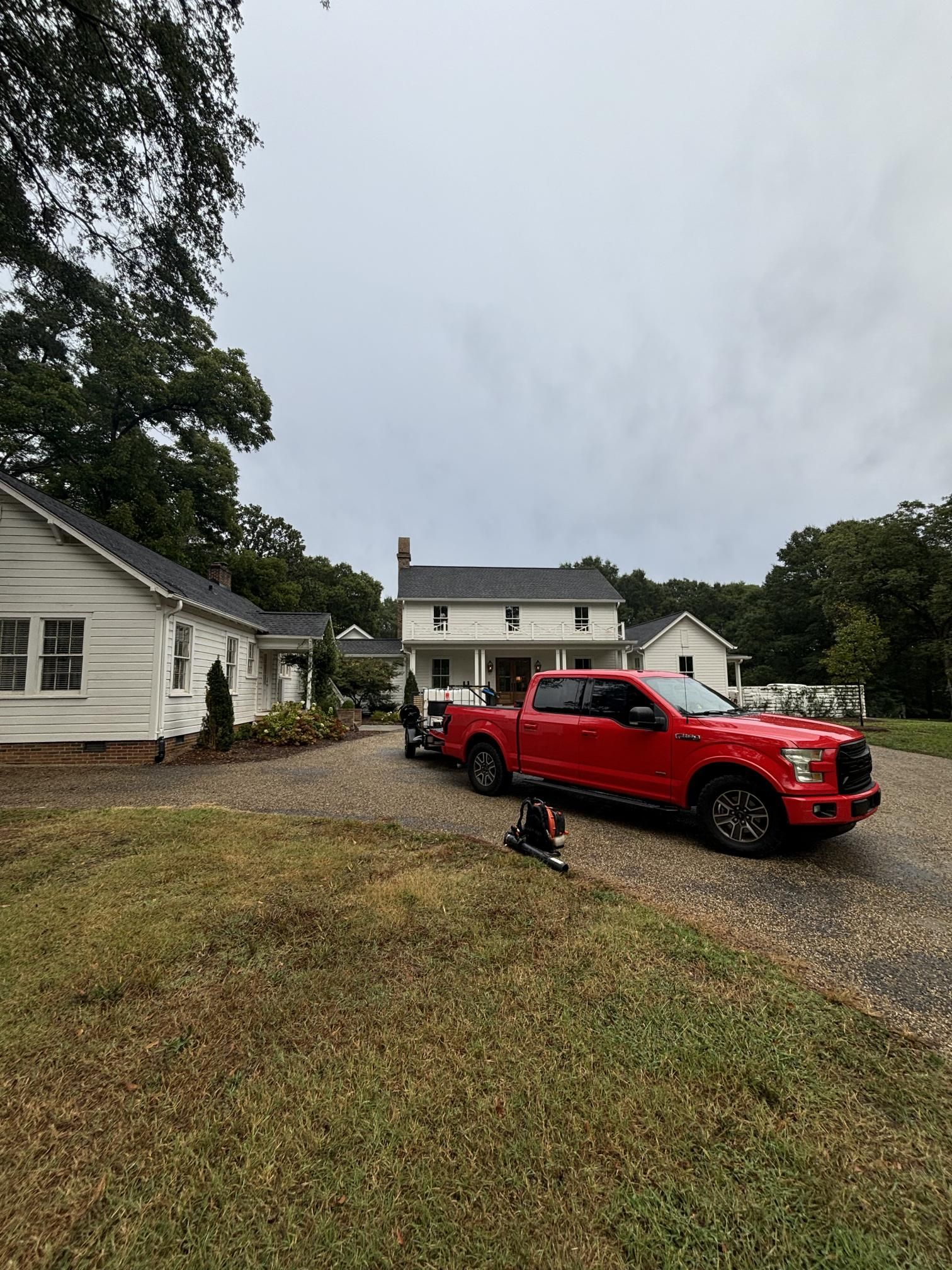 A red truck is parked in front of a white house.