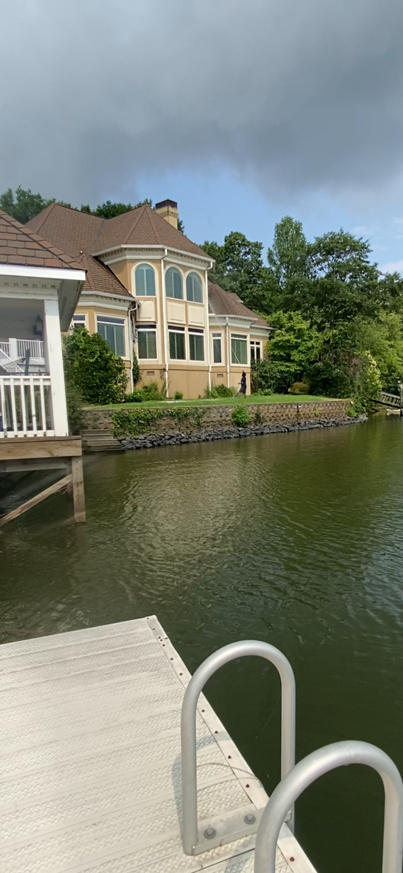 A large house is sitting on the shore of a lake next to a dock.