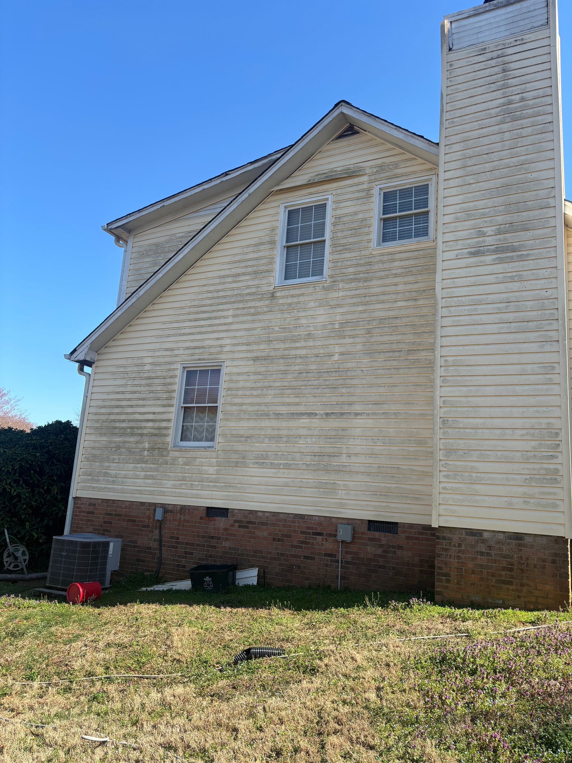The back of a white house with a lot of stains on it.
