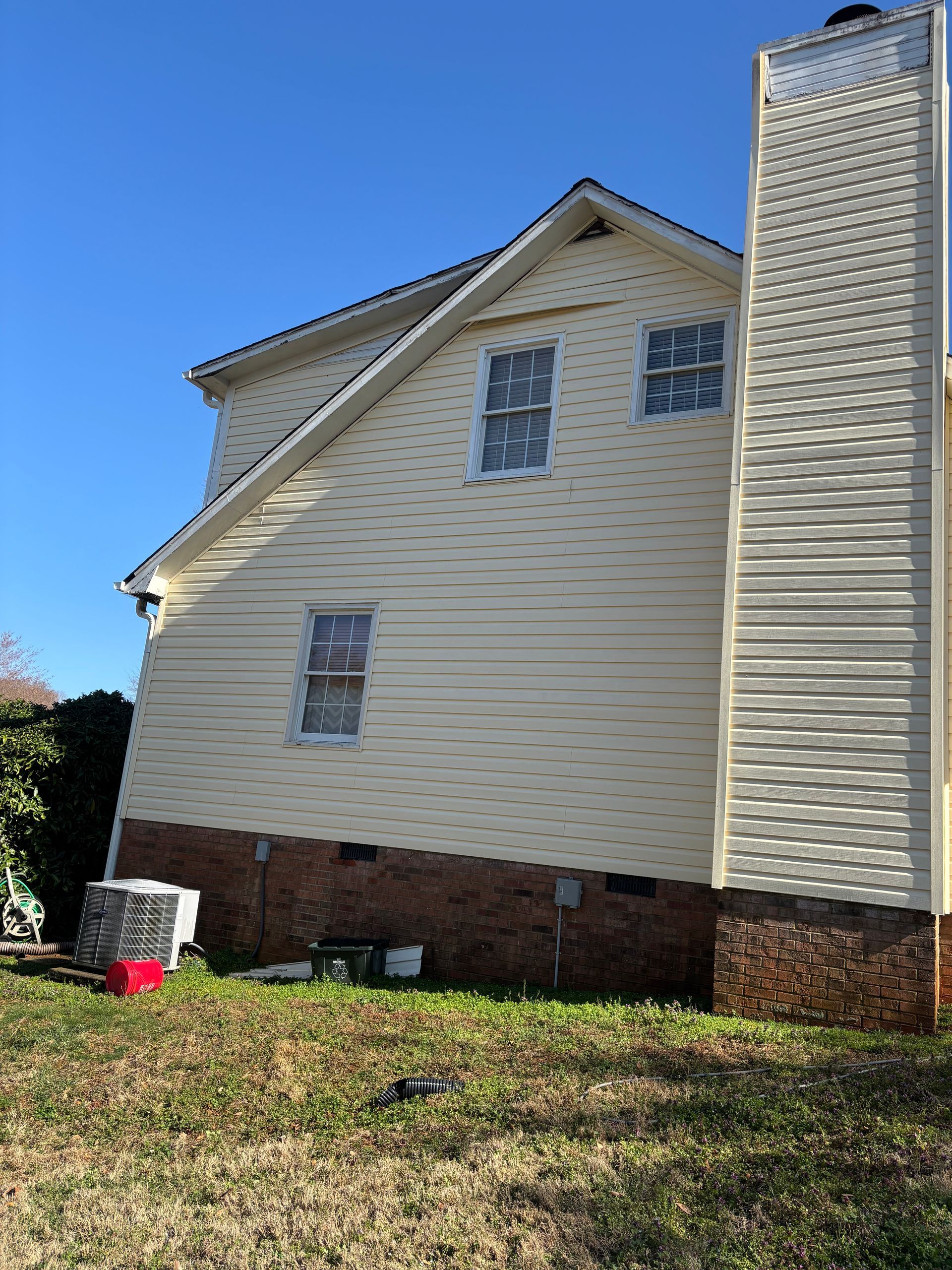 The back of a white house with a lawn in front of it.
