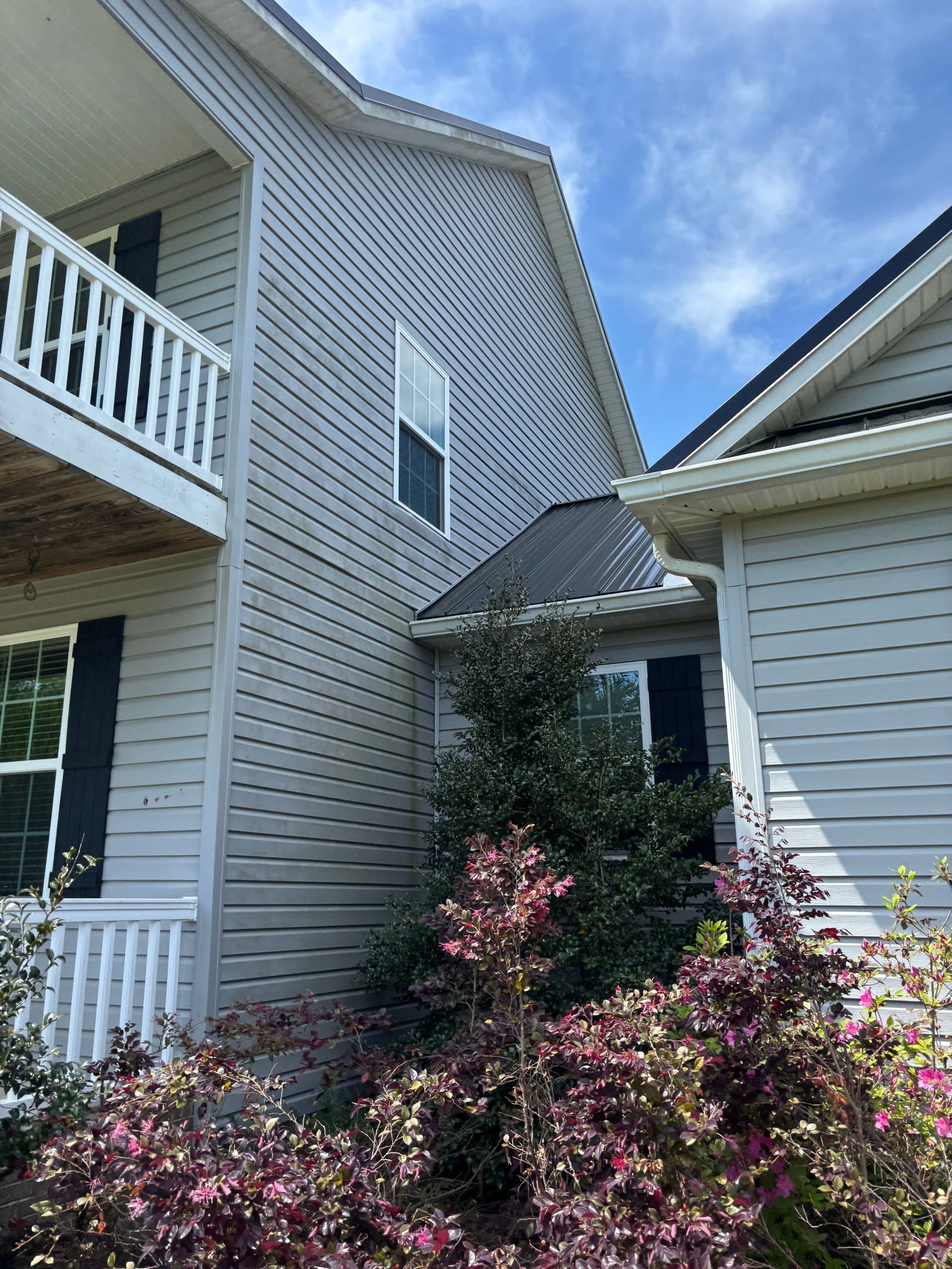 The back of a white house with a lot of stains on it.