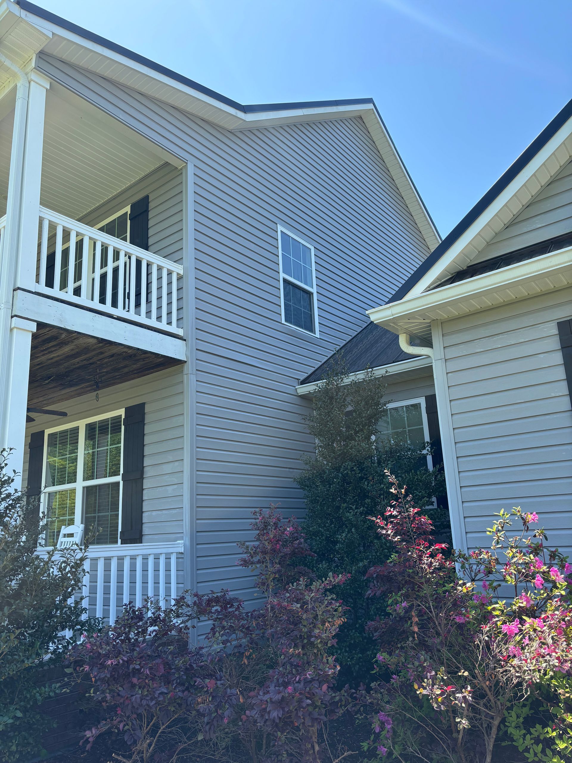 The back of a white house with a lawn in front of it.