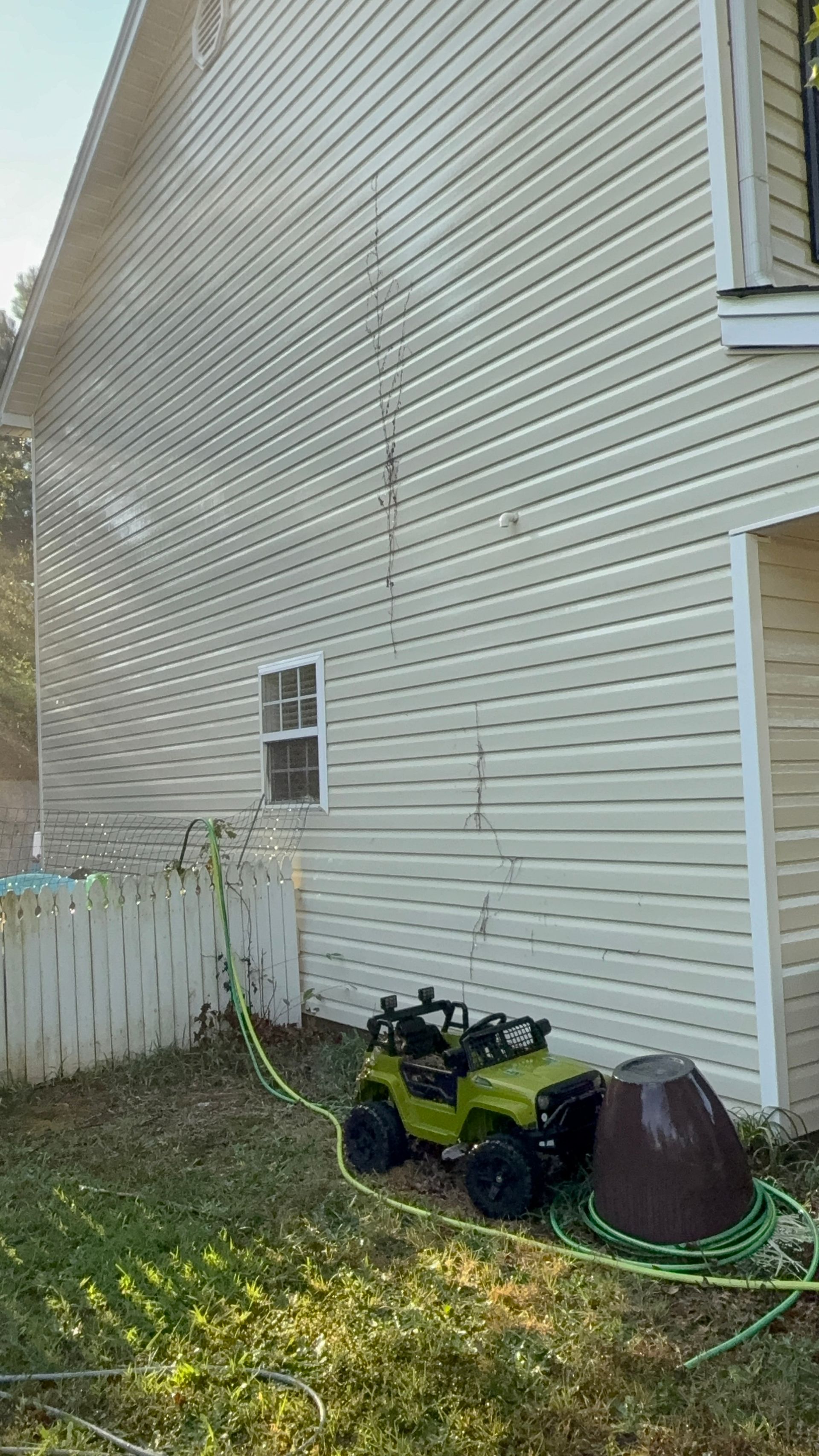 The back of a white house with a lawn in front of it.