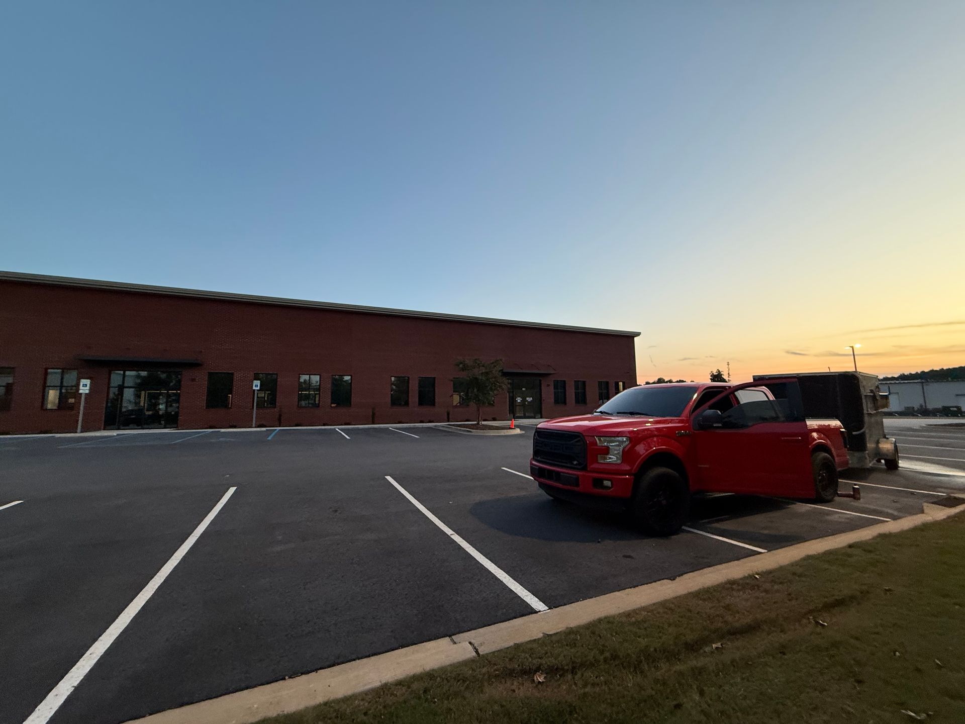Red truck parked outside brick building at dusk.
