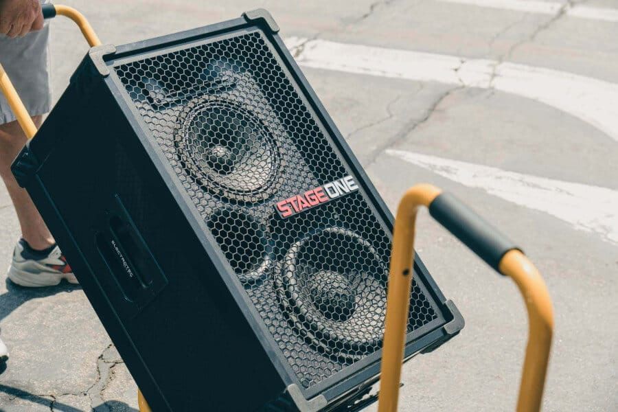 A man is standing next to a Soundboks 3 rental in a backyard.