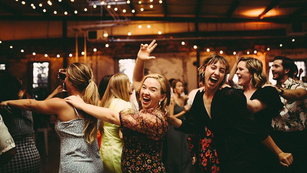 A group of people are dancing in a circle at a party.