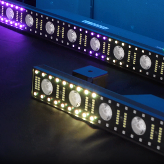 Two black light bars with white and colored LEDs illuminate a dark surface.