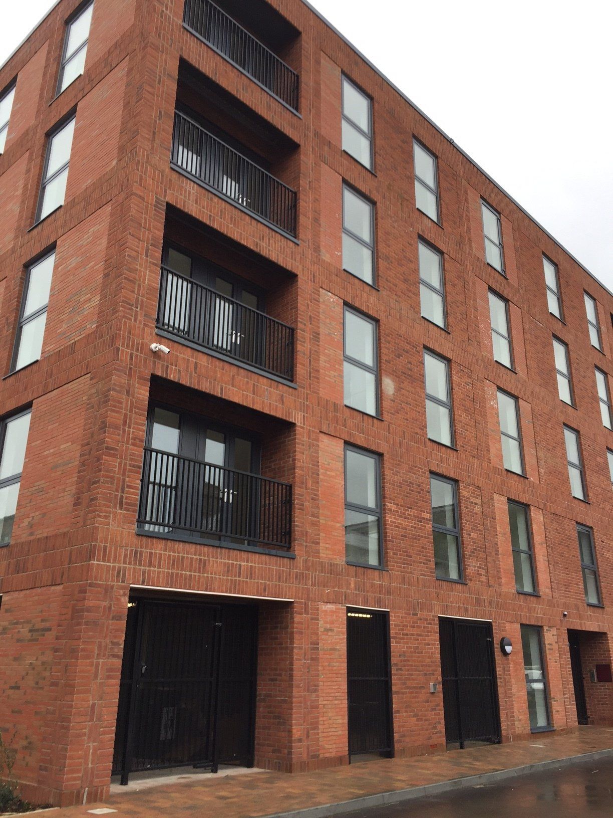 Red brick apartment building with black balconies and window frames.