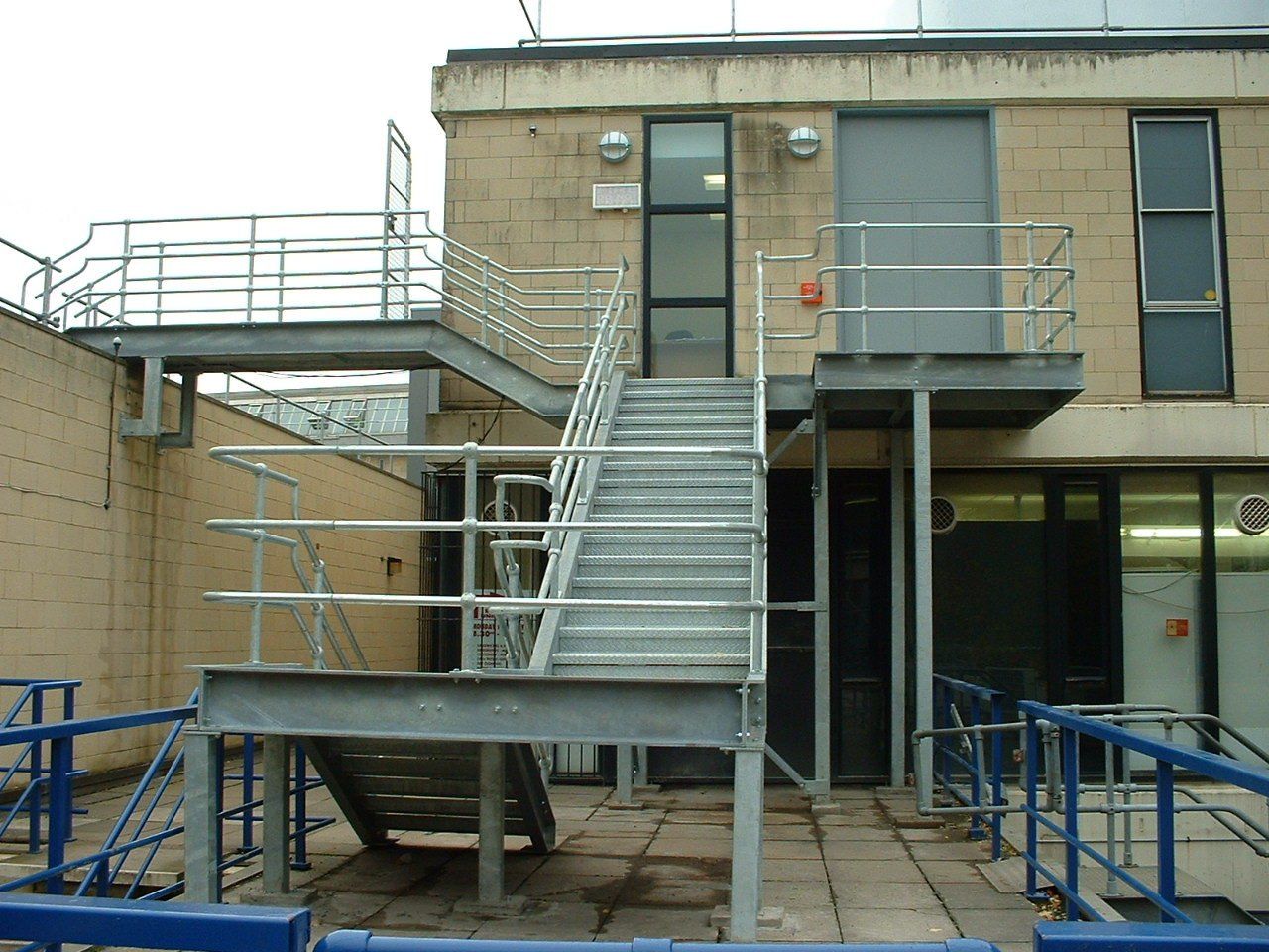 Exterior metal staircase leading to building entryways, with safety railings.
