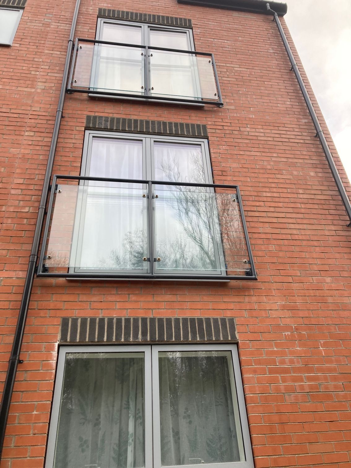 Red brick building with three balconies and windows.