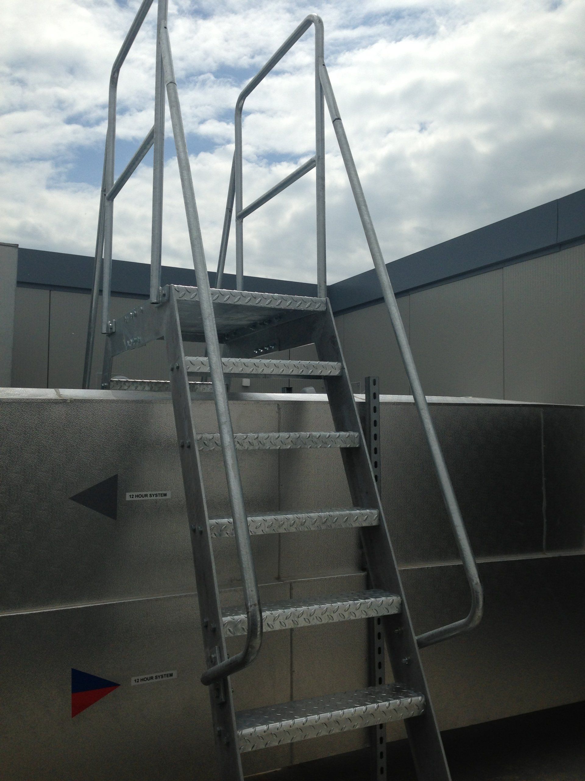 Metal ladder with handrails leads to a rooftop.