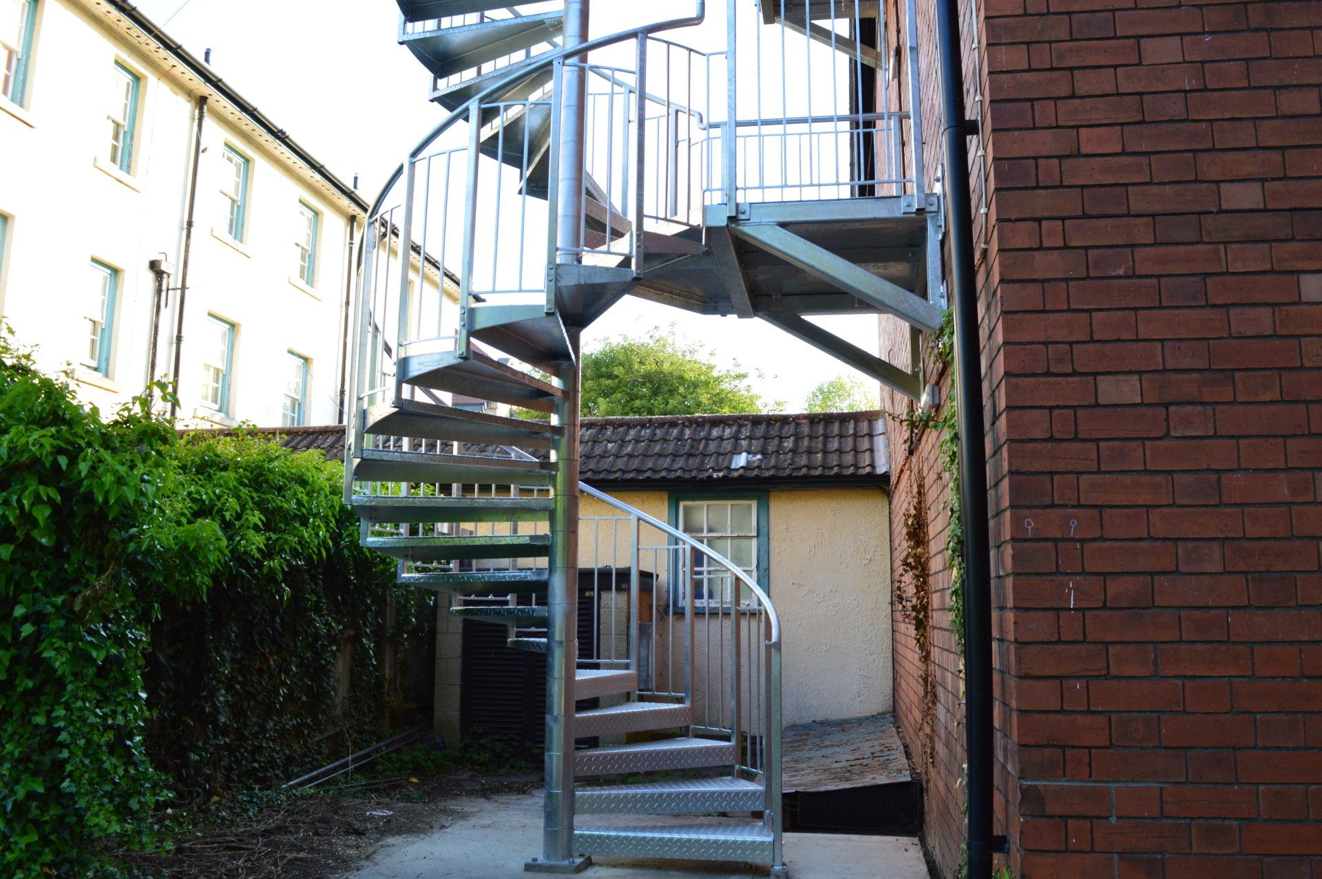 Spiral metal staircase attached to a brick building.