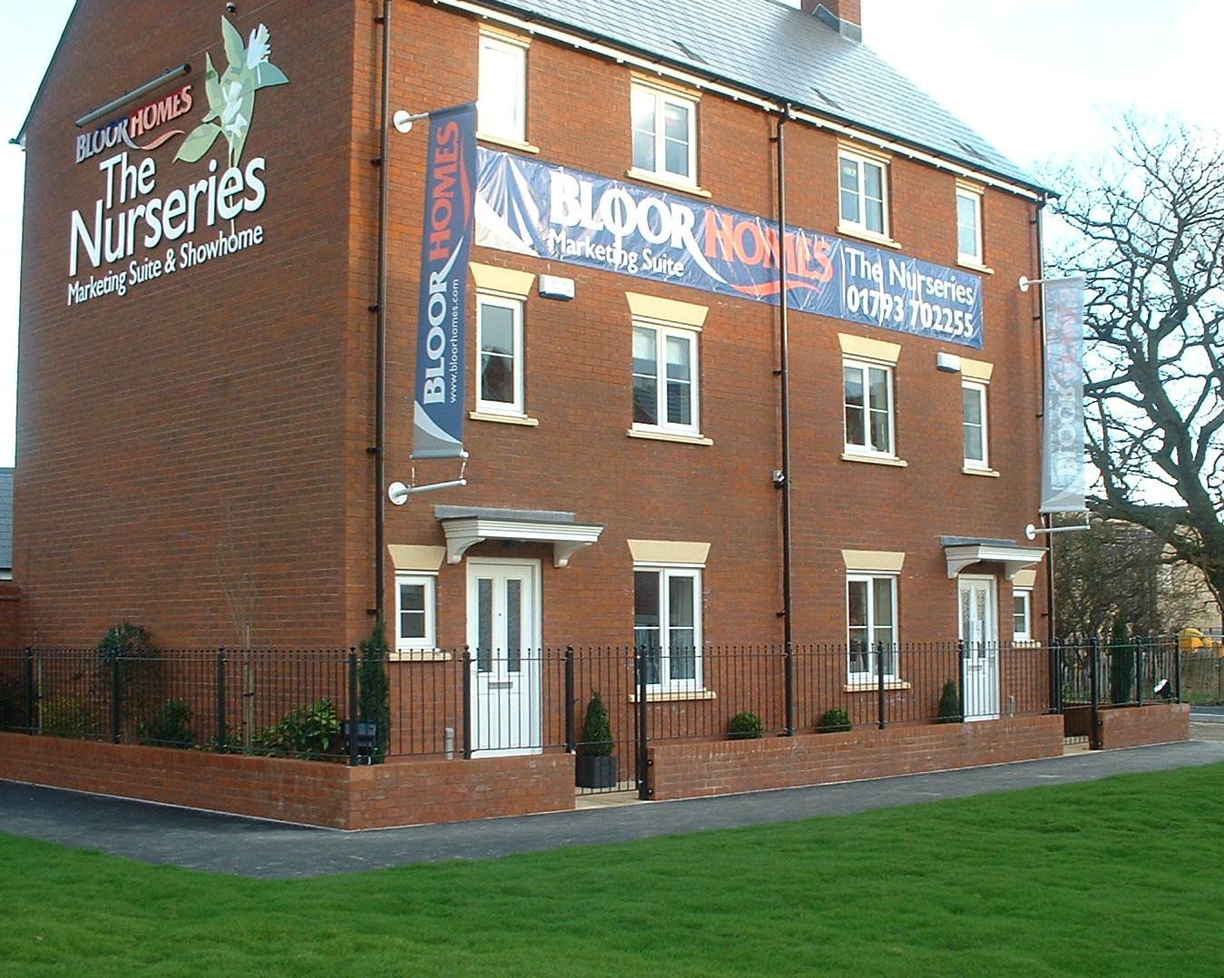 New brick houses for sale with signs in front, green lawn, clear sky.