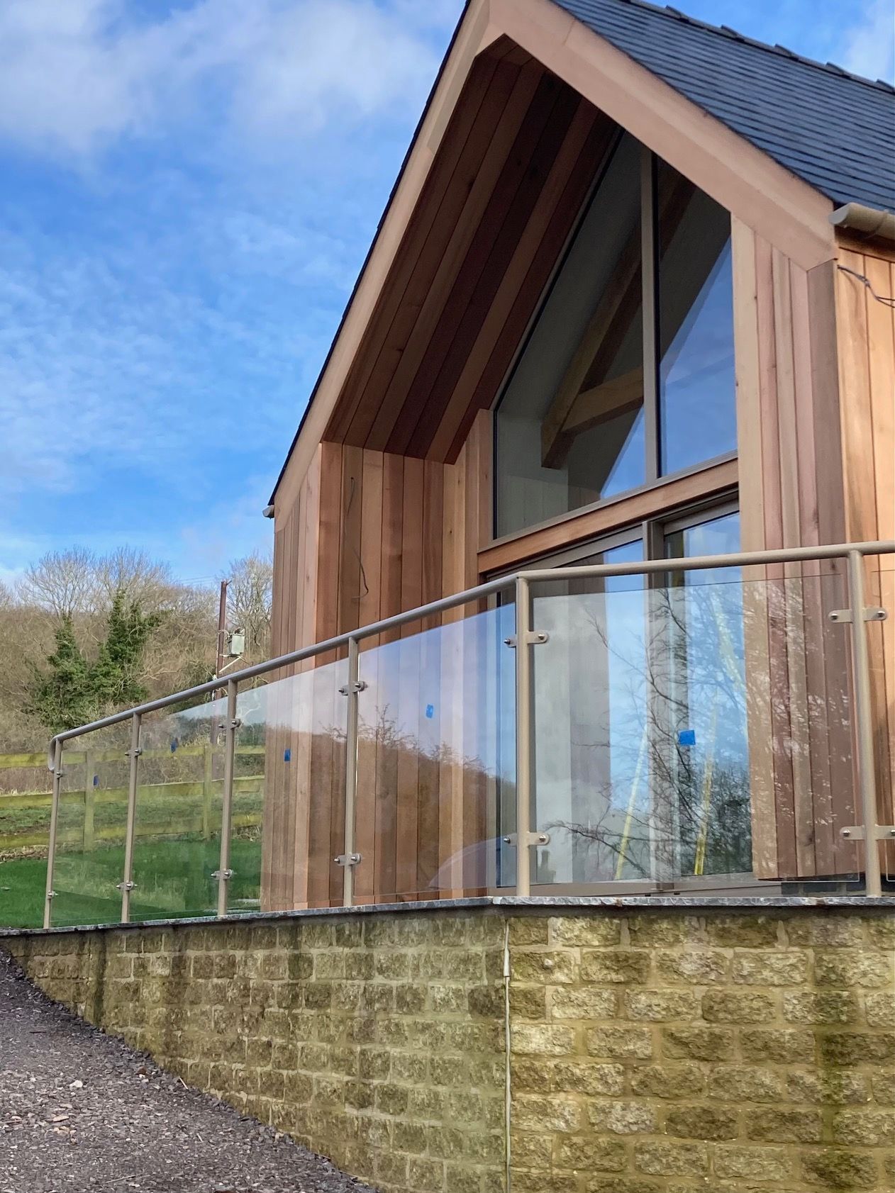 Modern wooden building with glass railing, clear sky.