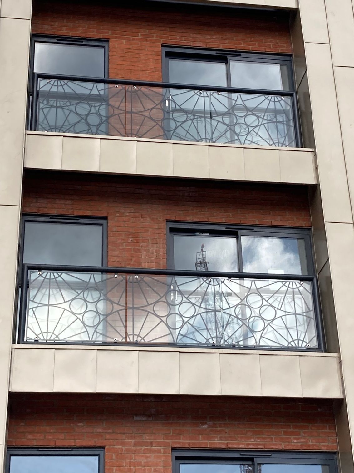 Multi-story brick building with balconies featuring decorative black metal railings.