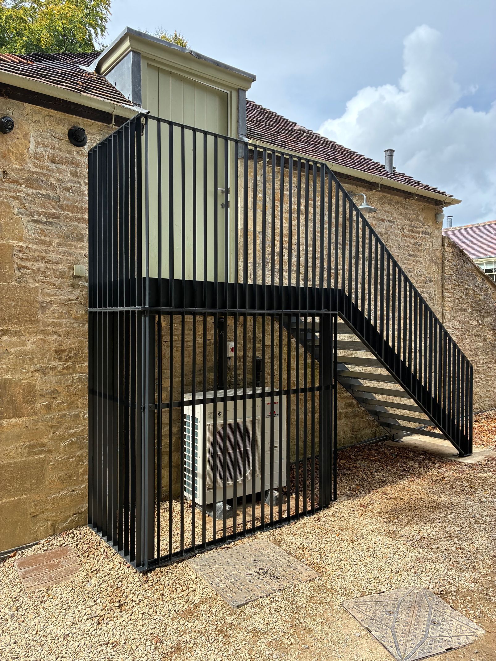 Black metal staircase and enclosure outside a brick building.