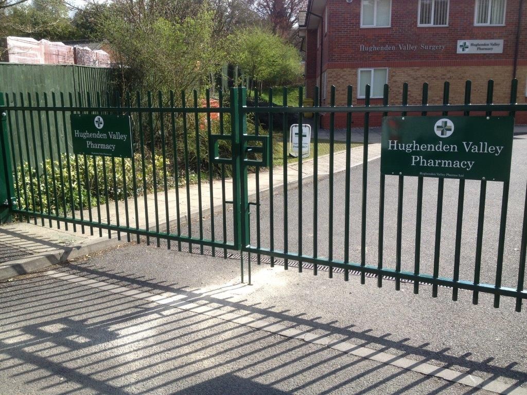Green metal gate with two signs,
