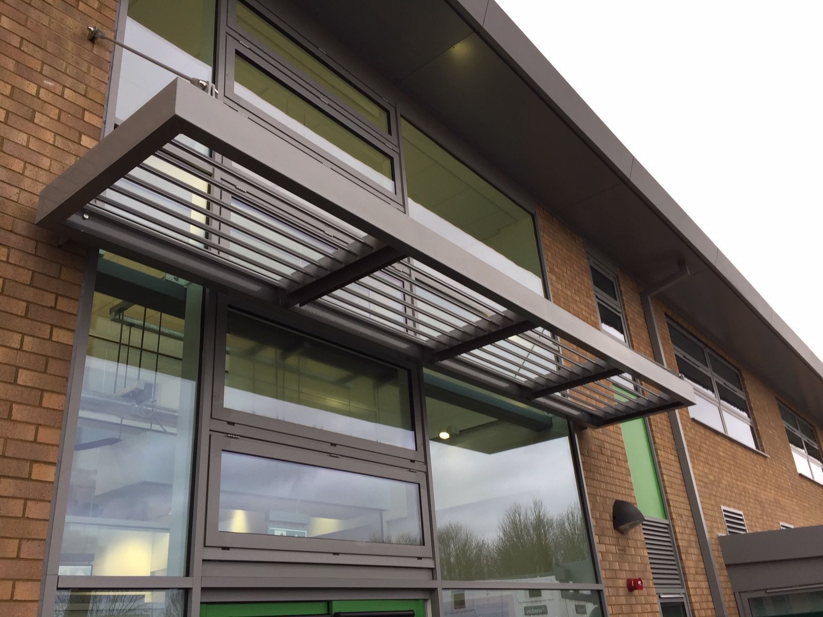 Modern building exterior with metal awning over windows, brick and glass.