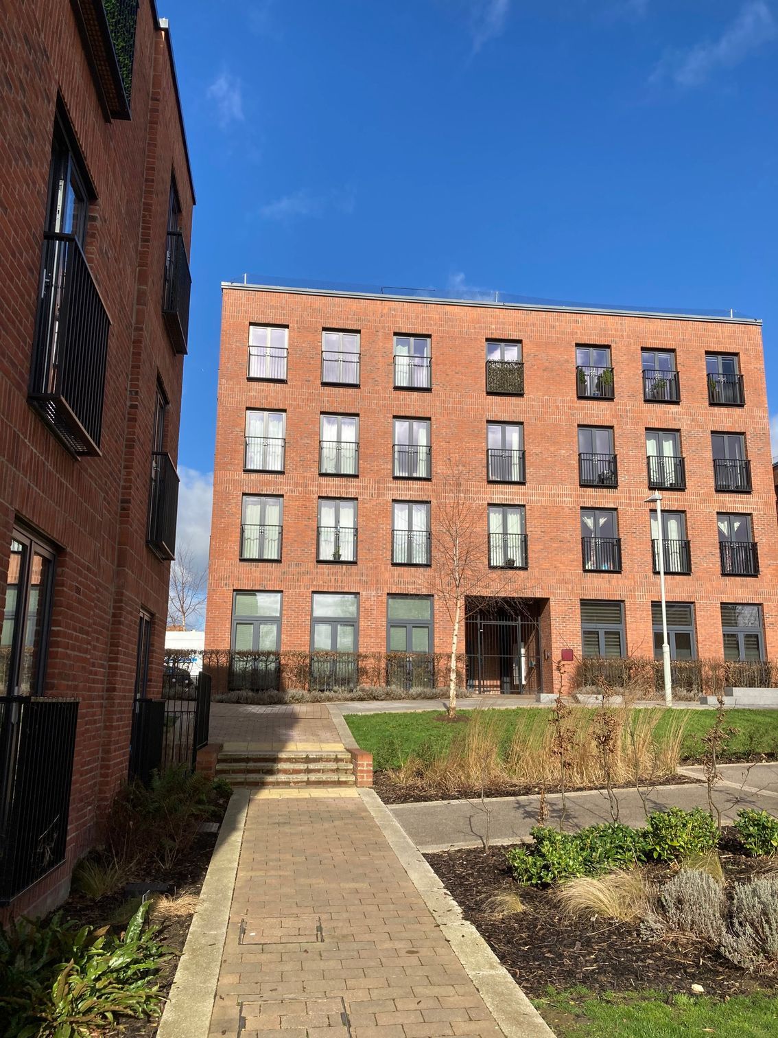 Brick apartment buildings with a walkway leading to the entrance; blue sky.