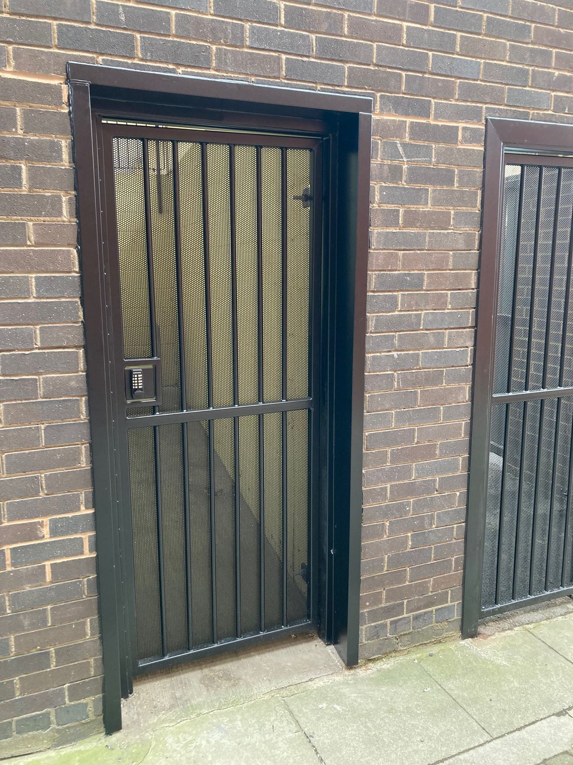 Black metal security door in a brick building.