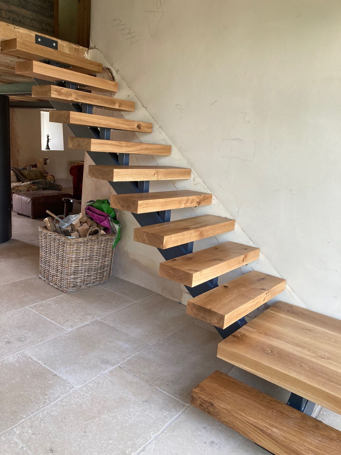 Wooden floating staircase with dark metal supports against a light-colored wall.