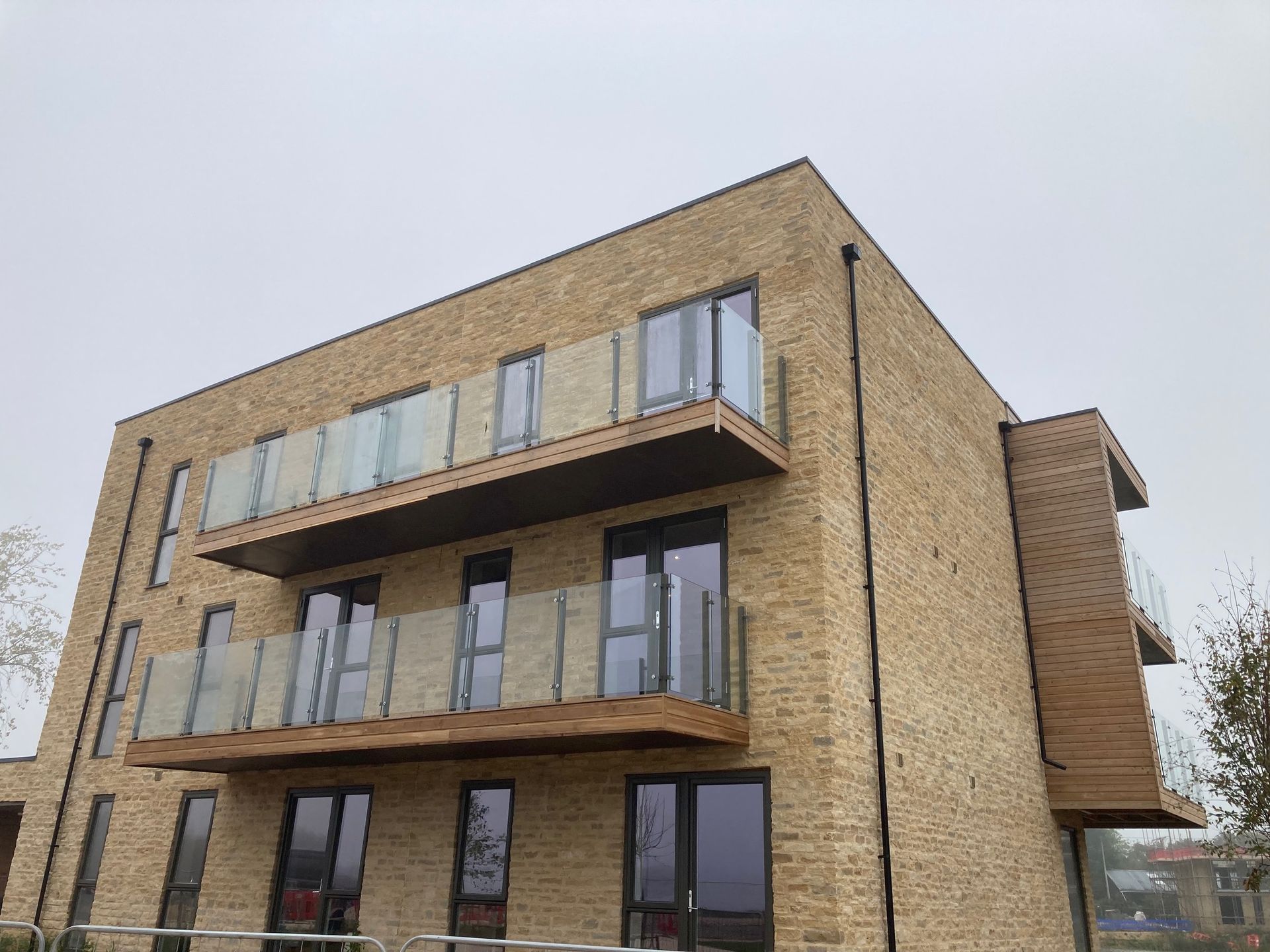 Modern brick apartment building with glass balconies against a cloudy sky.