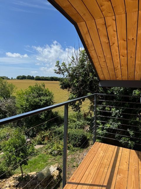 Metal railing, looking out at a green field and blue sky.
