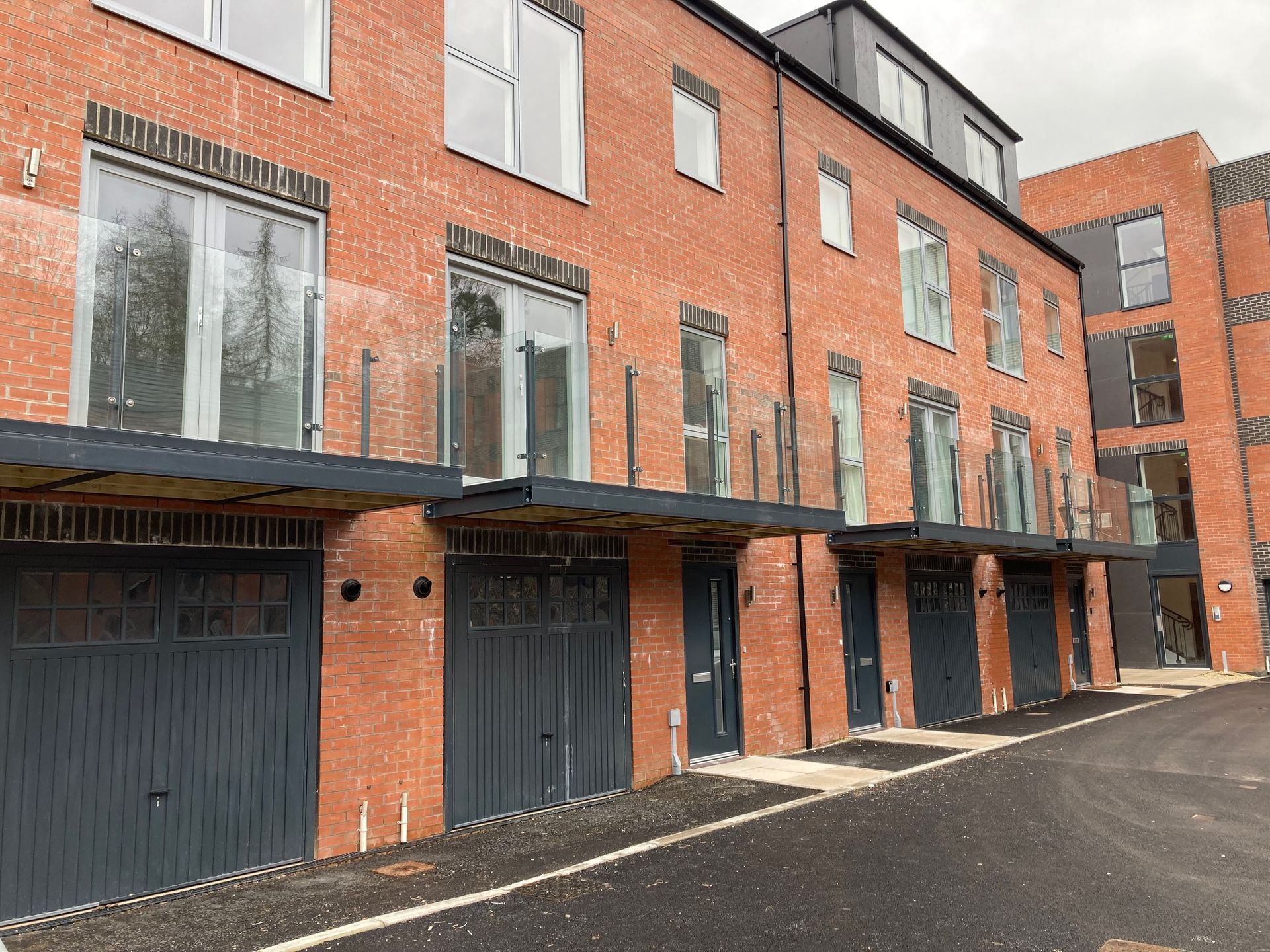 Red brick townhouses with gray garage doors and glass balconies.