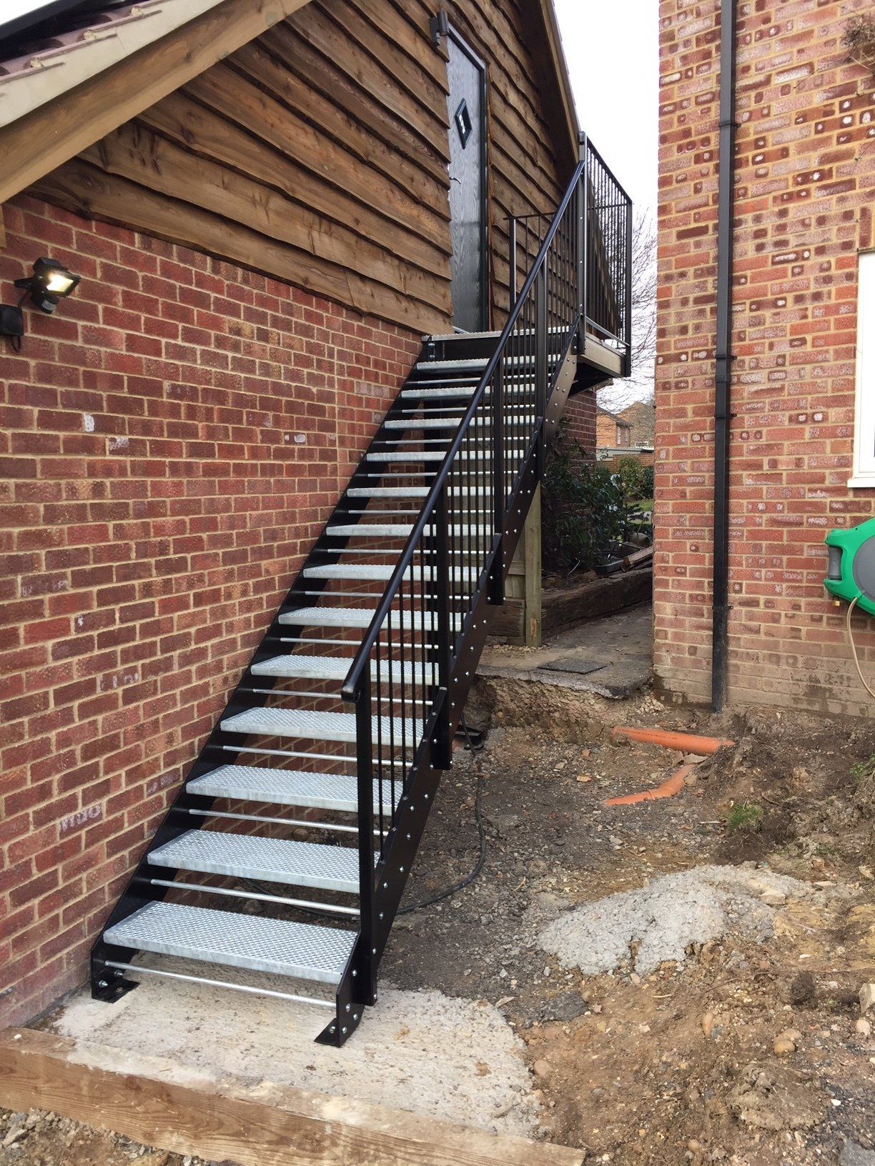 Black metal exterior staircase against a brick and wood building.
