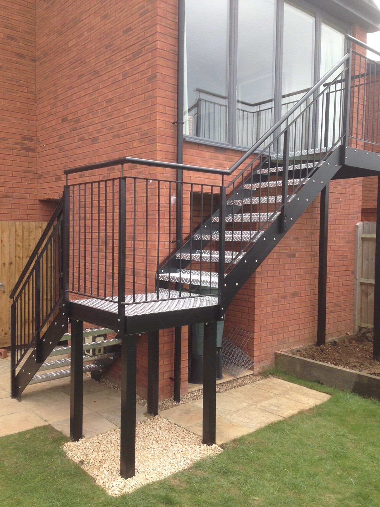 Black metal outdoor staircase against a brick building, with handrails and a landing.