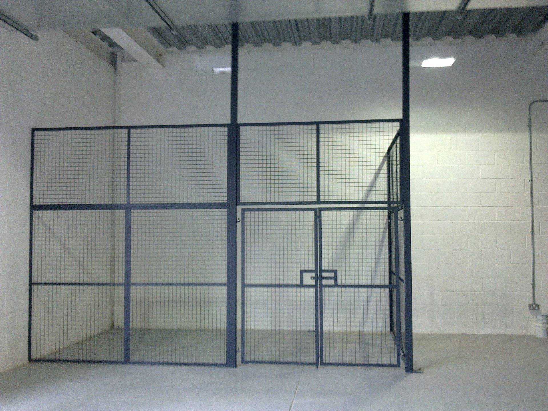 Metal security cage with a door in a warehouse.