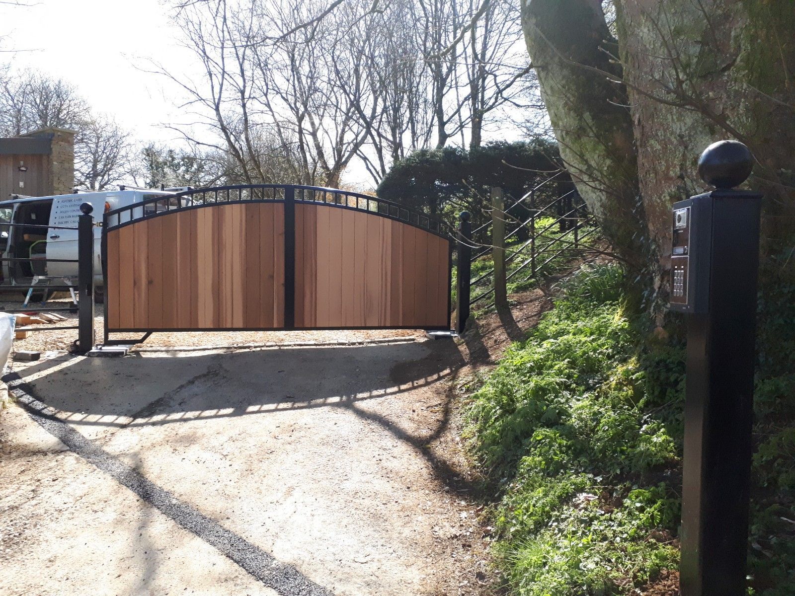 Wooden driveway gates with black metal frame and posts.
