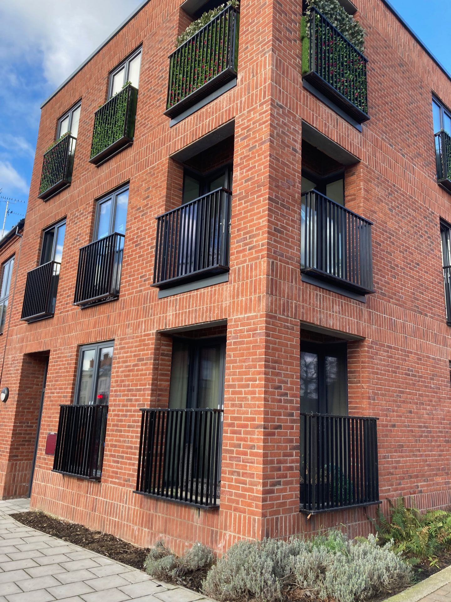 Red brick apartment building with black balconies and windows.