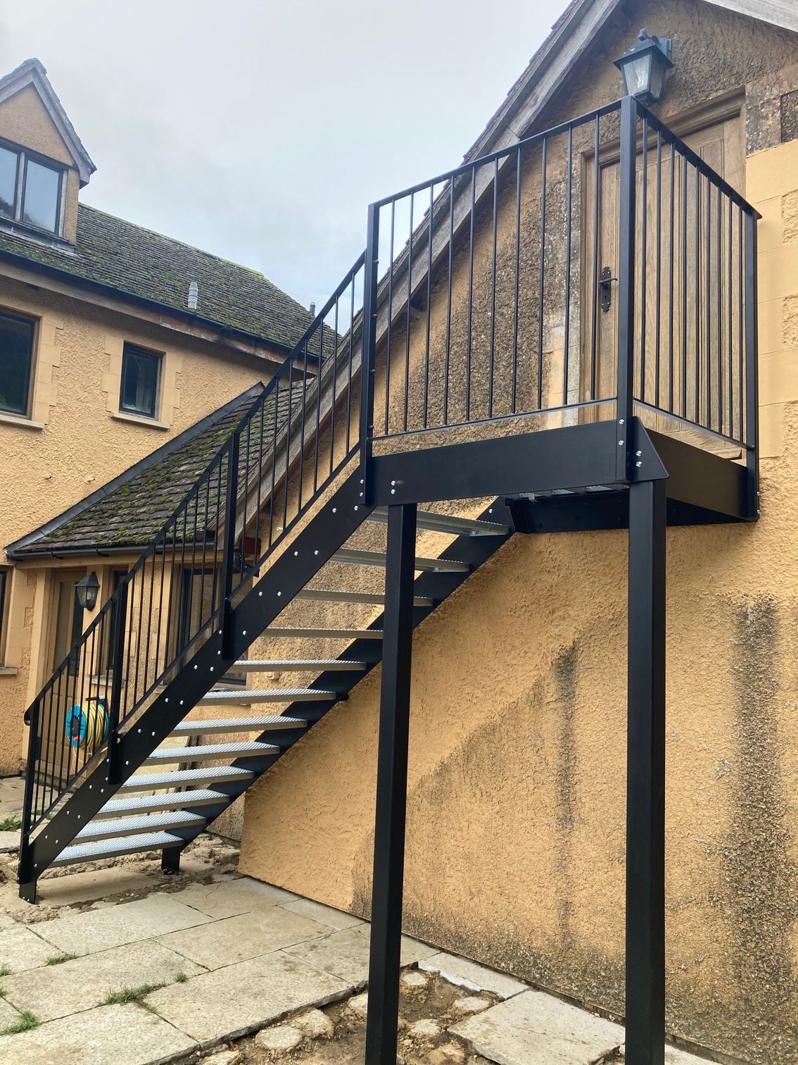 Black metal exterior staircase leading up to a small door, attached to a light beige building.