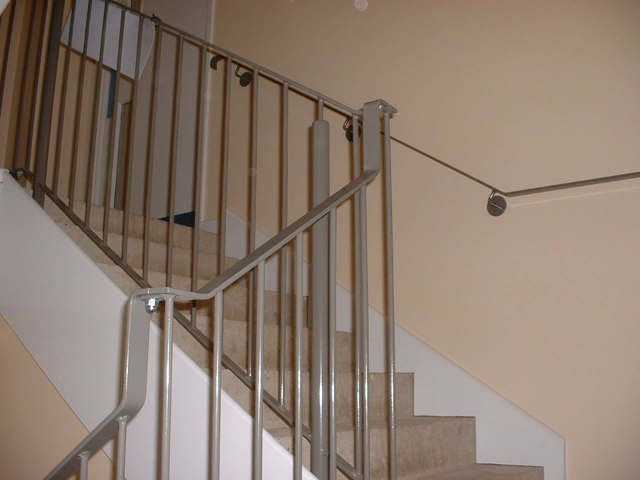 Staircase with metal railing; cream-colored walls and carpeted stairs.