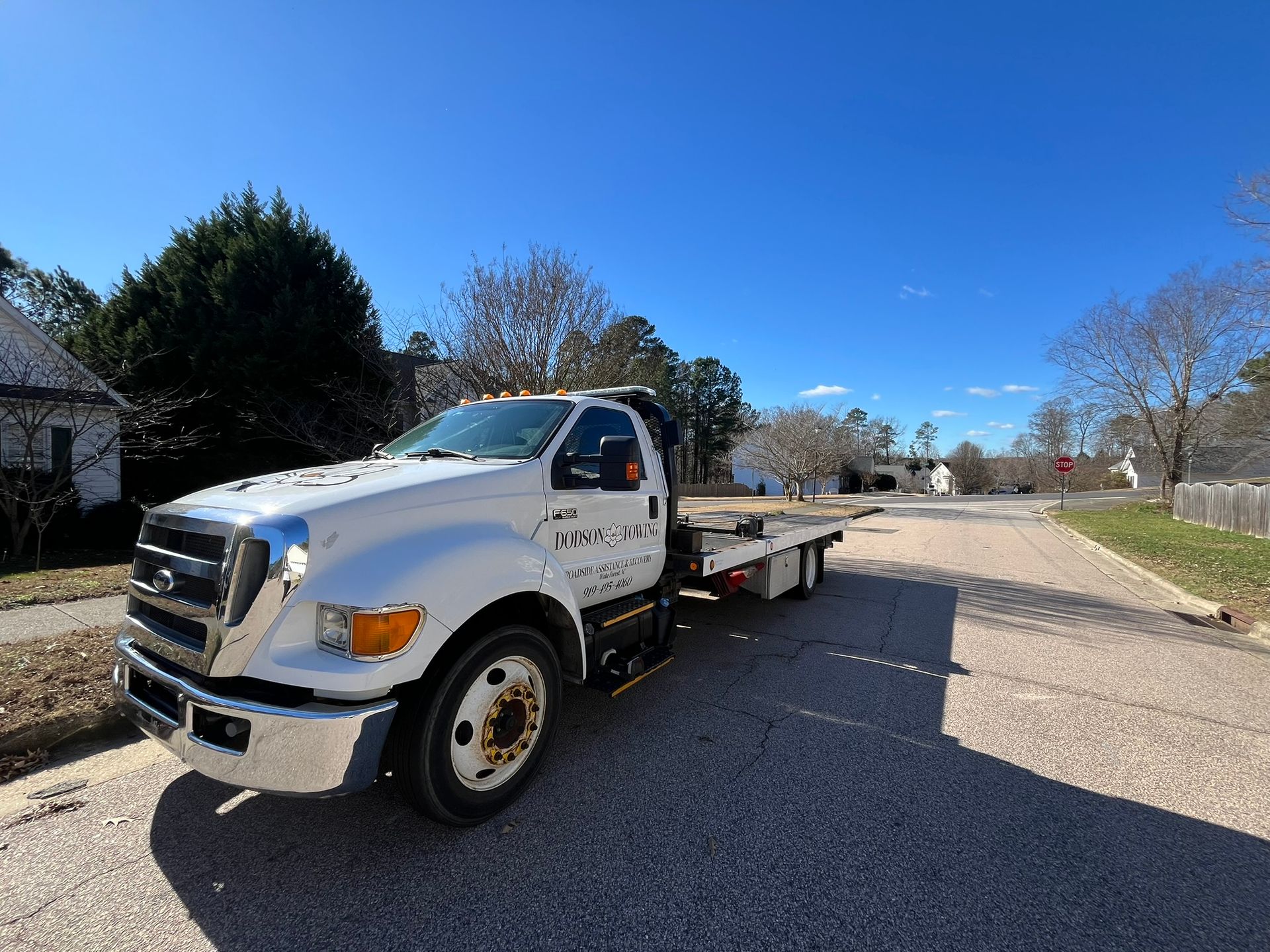 A white tow truck is parked on the side of the road.