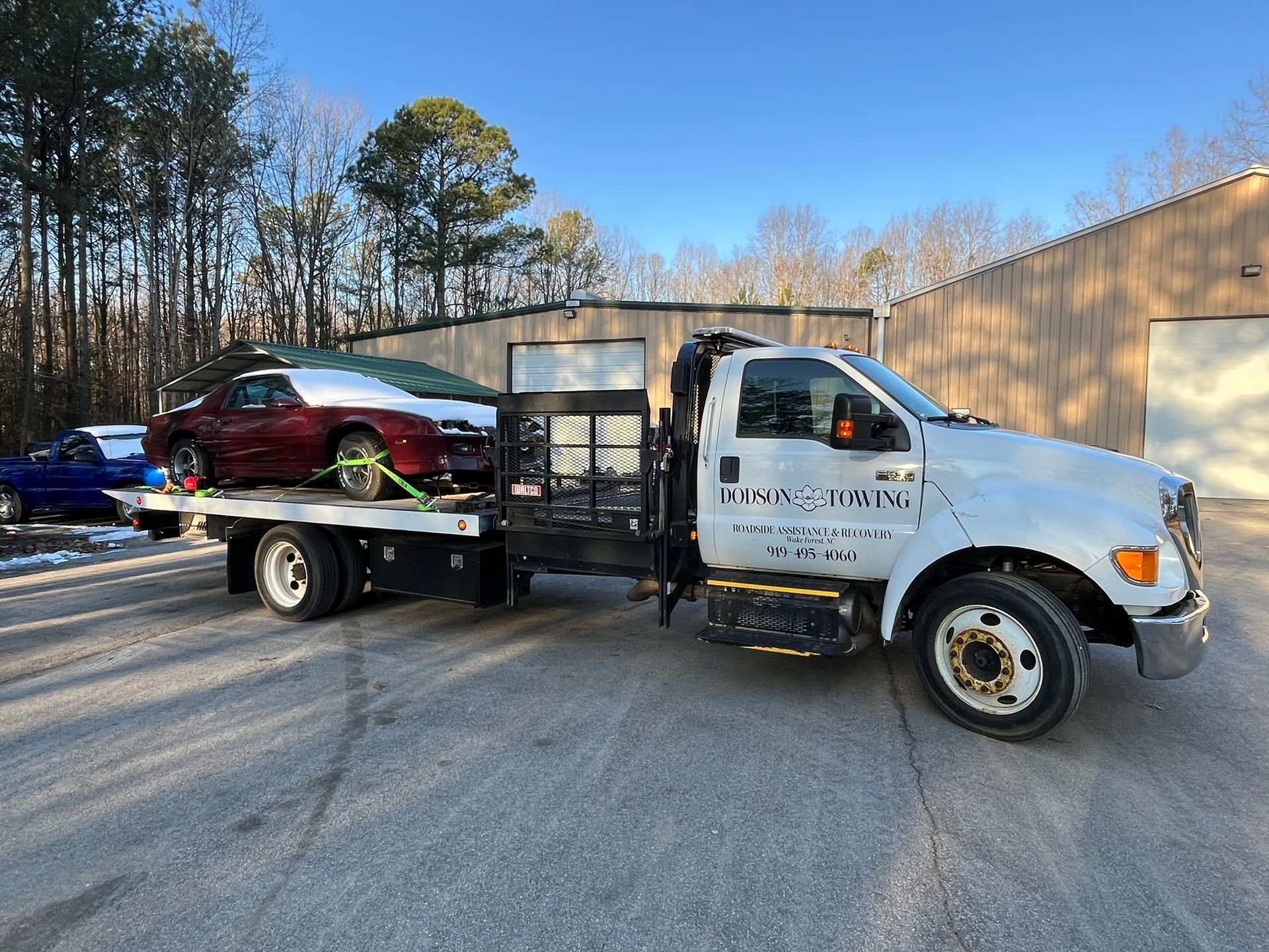 A tow truck is carrying a car on the back of it.