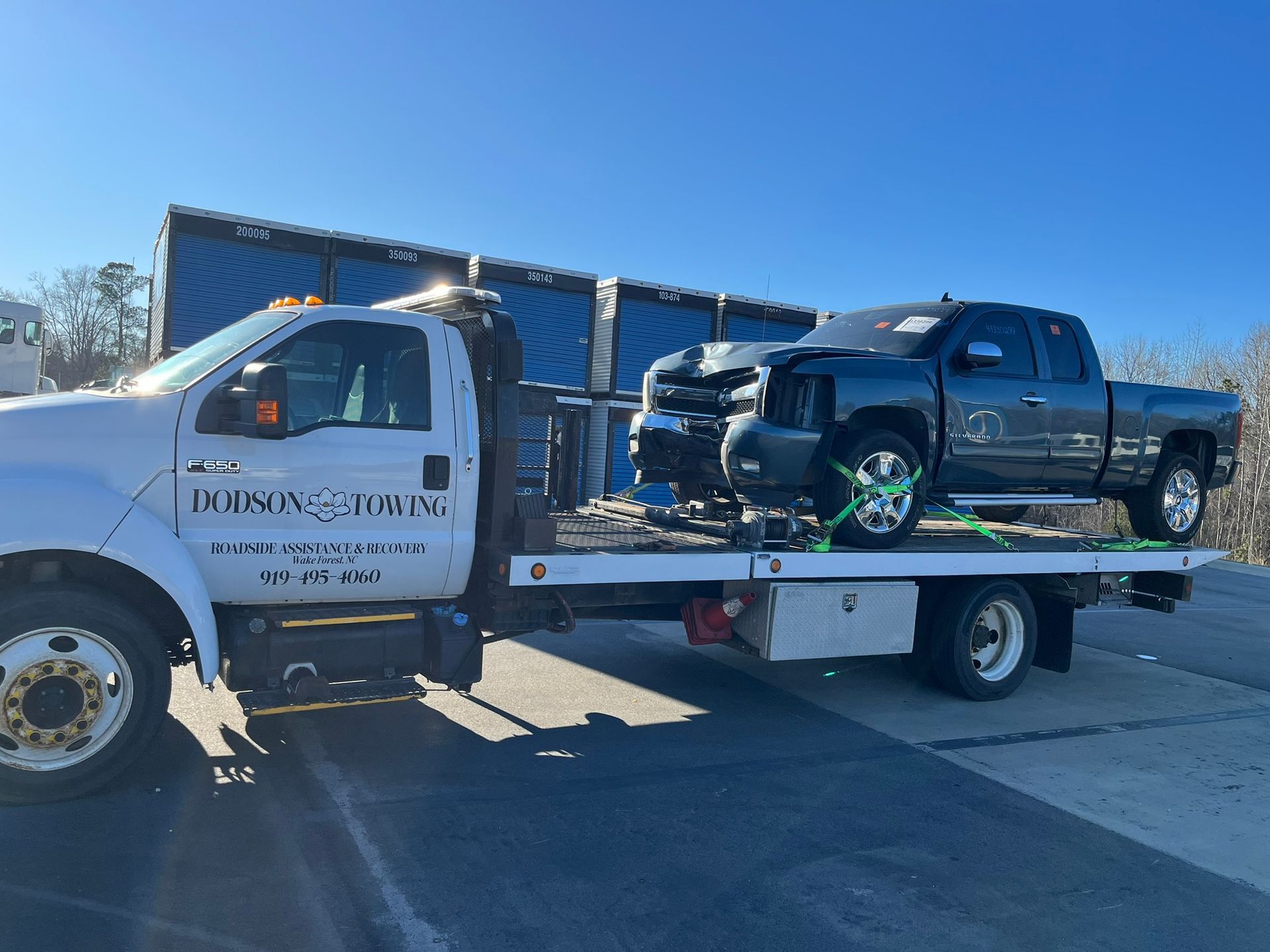 A tow truck with two trucks on the back of it.