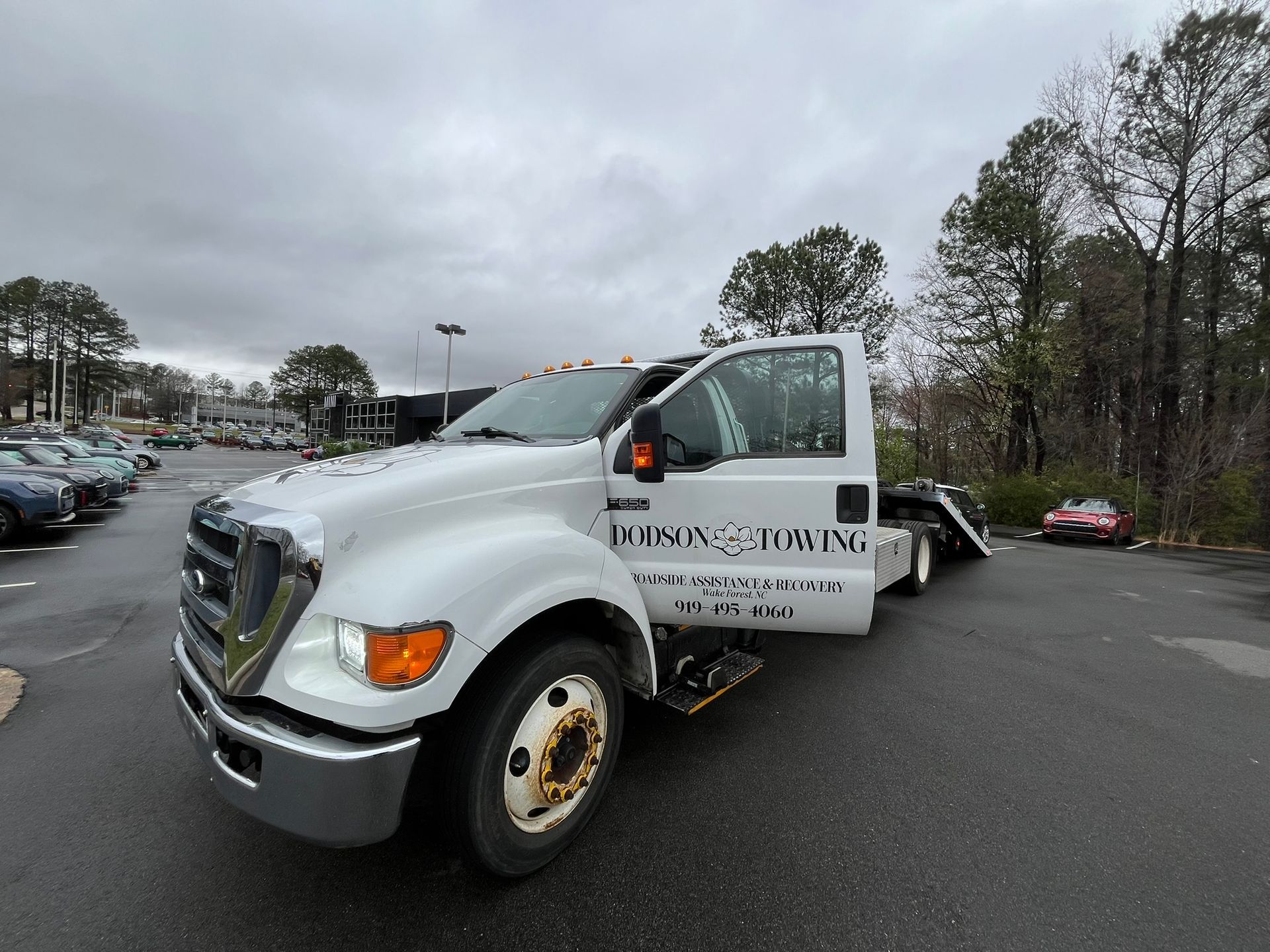 A white tow truck is parked in a parking lot.